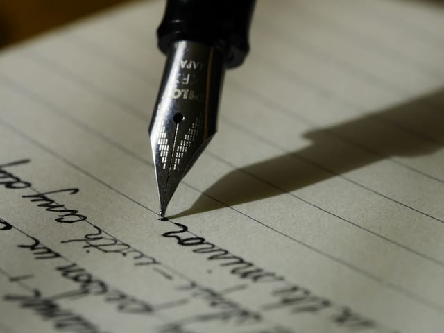 A notebook and pen in use on a desk