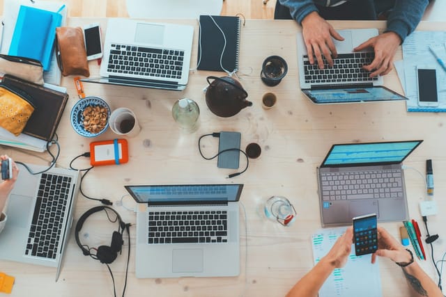 People collaborating with laptops around a shared desk